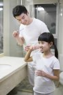 Chinese father and daughter brushing teeth — Stock Photo