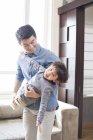 Chinese father playing and holding son at home — Stock Photo