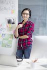 Cinese designer donna in piedi in ufficio a parete con schizzi — Foto stock