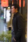 Pensivo chinês homem de pé na rua e olhando para longe — Fotografia de Stock