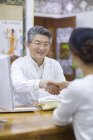 Médico chinês apertando as mãos com mulher no escritório — Fotografia de Stock