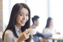 Chinese woman drinking coffee in cafe — Stock Photo