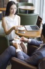 Chinese business people talking with coffee and laptop — Stock Photo