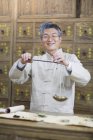 Farmacista cinese in piedi con bilancia di peso in farmacia — Foto stock