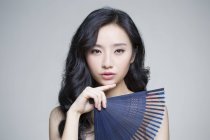 Chinese woman posing with folding fan — Stock Photo