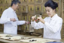 Reife Chinesin wägt Kräuter in Apotheke — Stockfoto