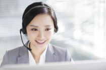 Empresária chinesa usando fone de ouvido no local de trabalho — Fotografia de Stock