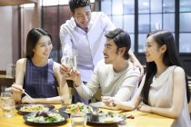 Chinese friends clinking glasses in restaurant — Stock Photo