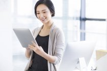Китаянка использует цифровой планшет в офисе — стоковое фото