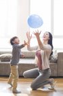 Chinês mãe e filho brincando com balão em casa — Fotografia de Stock