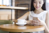 Mulher chinesa usando smartphone no café — Fotografia de Stock