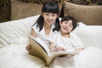 Enfants chinois au repos avec livre au lit — Photo de stock