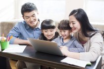 Chinese parents with kids using laptop in living room — Stock Photo