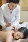 Mature woman performing acupuncture treatment on female patient — Stock Photo