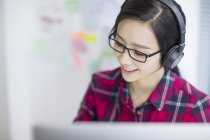 Mulher chinesa ouvindo música no escritório — Fotografia de Stock