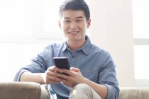 Китайська чоловік холдингу смартфон і дивлячись в камери — стокове фото
