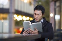 Homem chinês lendo livro no café de rua — Fotografia de Stock