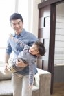 Chinese father playing and holding son at home — Stock Photo
