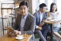 Empresário chinês usando tablet digital no café — Fotografia de Stock