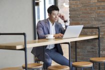 Китайський бізнесмен, робота з ноутбука в кафе — стокове фото