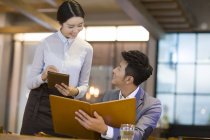 Hombre chino pidiendo en restaurante con camarera - foto de stock