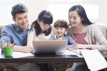Genitori cinesi con bambini che usano il computer portatile in soggiorno — Foto stock
