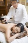 Senior Chinese doctor performing scrapping massage on female patient — Stock Photo