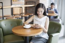 Mujer china usando smartphone en cafetería - foto de stock