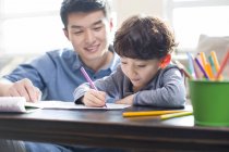 Filho chinês fazendo lição de casa com o pai — Fotografia de Stock