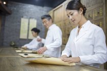 Chinese doctors packing herbs in traditional pharmacy — Stock Photo