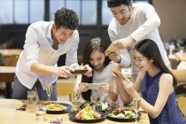 Chinesische Freunde fotografieren Gerichte im Restaurant — Stockfoto
