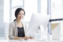 Mujer china trabajando con computadora en la oficina - foto de stock