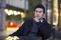 Pensive Chinese man sitting at street cafe — Stock Photo
