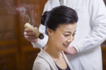 Doctor performing moxibustion therapy on mature woman — Stock Photo