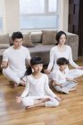 Chinese family meditating in living room — Stock Photo