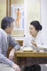 Femme médecin chinois parler avec le patient âgé — Photo de stock
