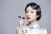 Donna cinese in abito tradizionale con rossetto in mano — Foto stock