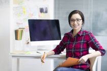 Designer chinesa sentada no escritório com caderno de esboços — Fotografia de Stock