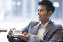 Chinese man drinking coffee in cafe — Stock Photo