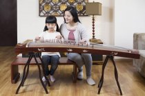 Chinese mother teaching daughter traditional musical instrument zither — Stock Photo