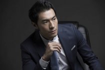 Retrato de empresario chino confiado sentado en sillón - foto de stock