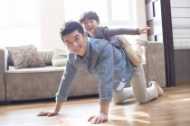 Chinese son playing and riding on father at home — Stock Photo