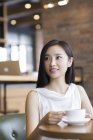 Китайська жінка, що сидить з кави в кафе — стокове фото