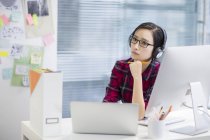 Китаянка слушает музыку в офисе — стоковое фото