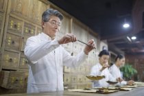 Chinesische Ärzte wiegen Kräuter in traditioneller Apotheke — Stockfoto