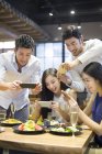 Amici cinesi che scattano foto di cibo nel ristorante — Foto stock