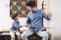 Китайский отец обучает сына традиционному музыкальному инструменту erhu — стоковое фото