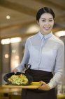 Camarera china sirviendo en restaurante - foto de stock