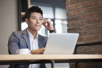 Китайський бізнесмен сидить з ноутбука в кафе — стокове фото