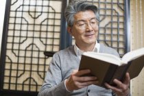 Senior Chinese man reading book — Stock Photo